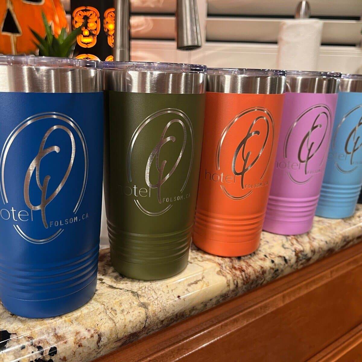 A customer order of branded tumblers in several colors, lined up on a counter