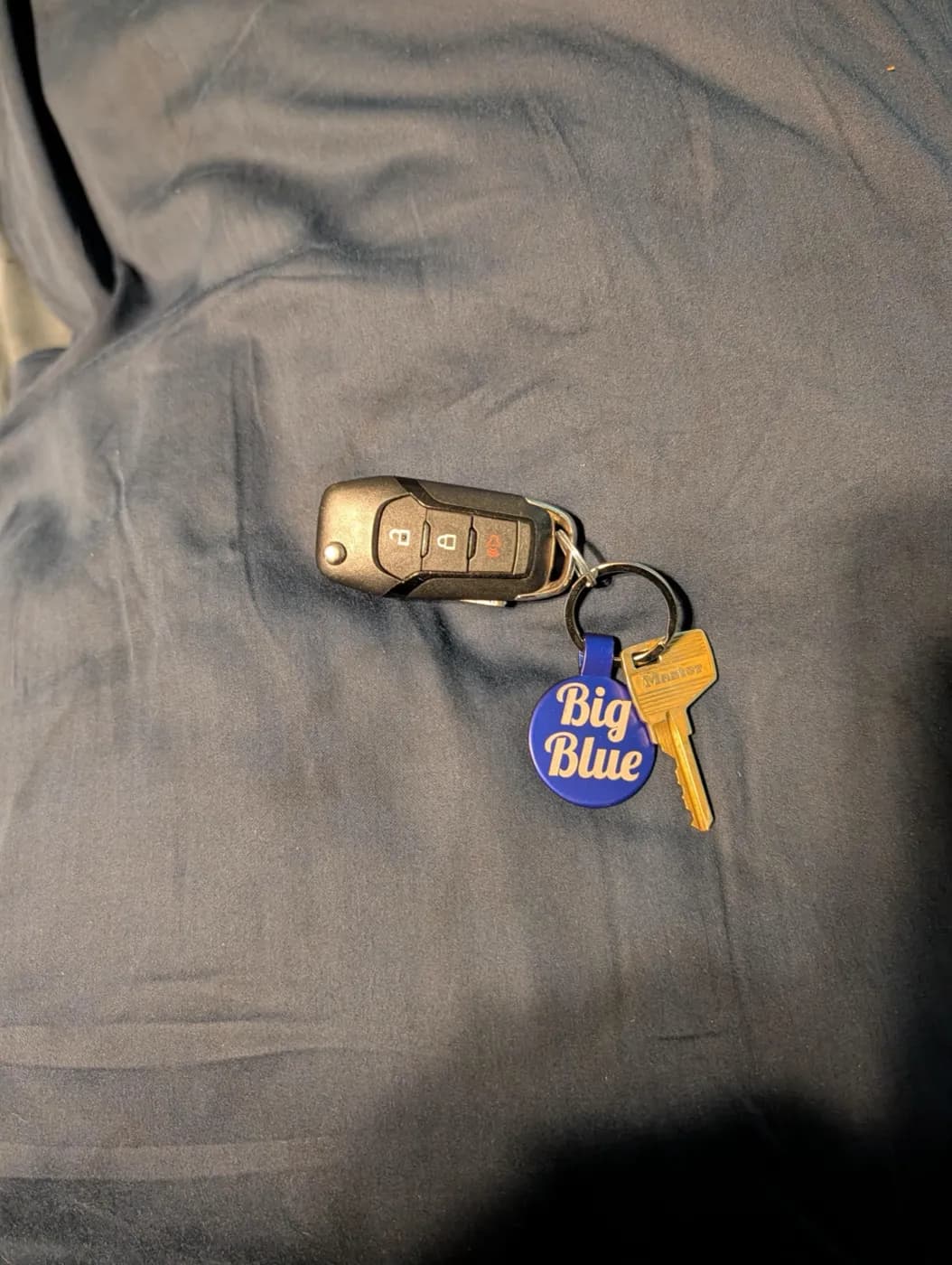 Round blue "Big Blue" keychain on a customer’s car keys